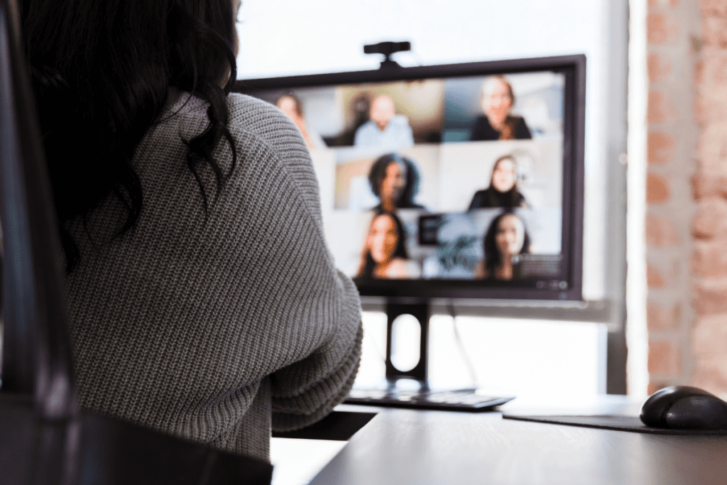 Back of dark haired lady looking at a computer during a video conference.