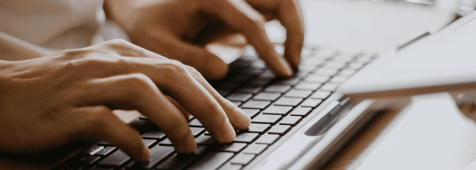 The image shows a close-up view of hands typing on a computer keyboard. The fingers are actively pressing the keys, suggesting someone is in the process of typing or working on the keyboard.