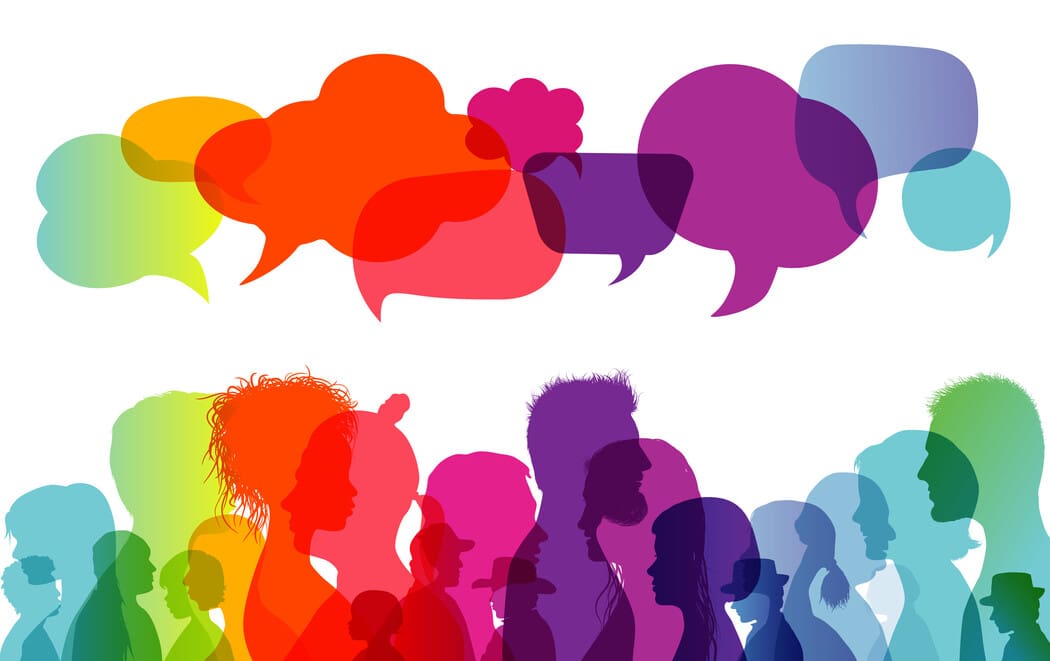 The image features a colorful array of silhouetted human profiles viewed in profile, positioned along the bottom half. Each silhouette varies in shape and size. The silhouettes are in a spectrum of colors including red, orange, yellow, green, blue, and purple, overlapping each other to create a vibrant effect. Above these profiles are large, vivid speech bubbles in shades of orange, red, pink, and purple, overlaying each other. 